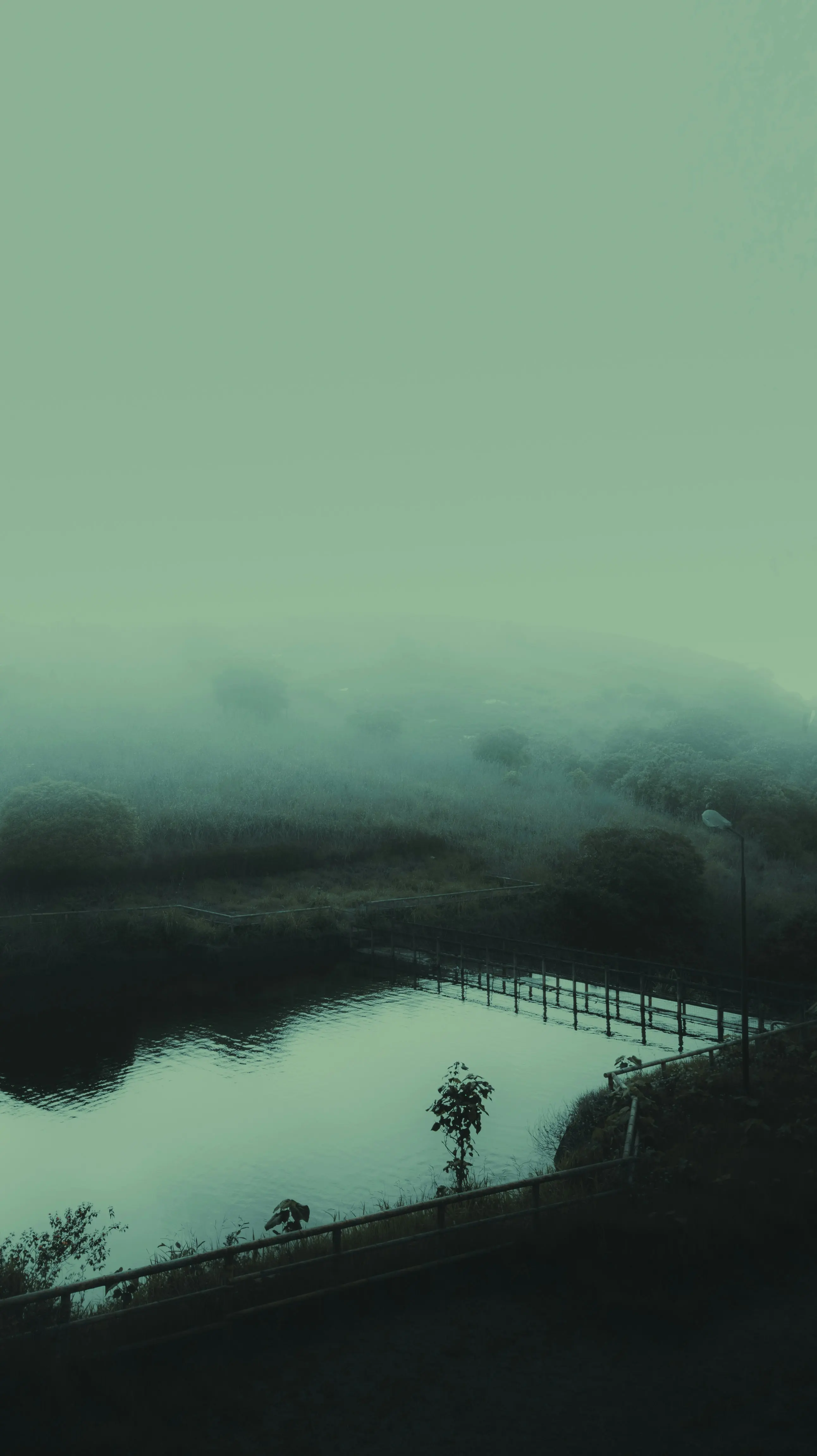A foggy lake with a fence, evoking the calm and deliberate approach to land ownership